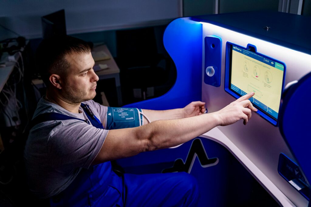 pexels-photo-12203707-12203707 A man uses a touch screen for a telemedicine health check in a modern setting.